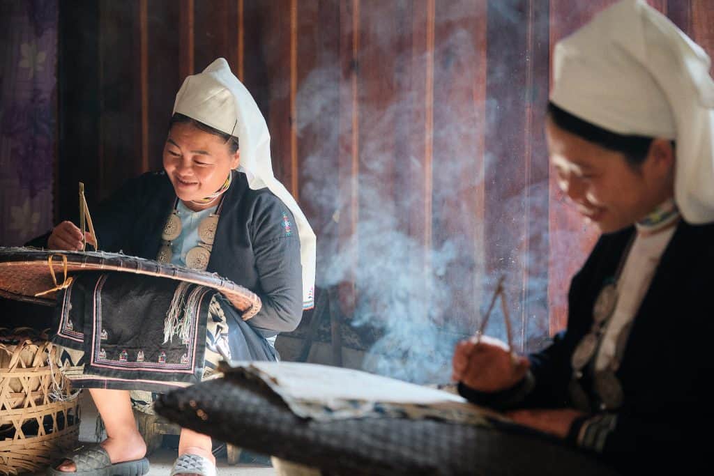 H'mong women weaving textiles in a traditional setting, showcasing Vietnam's rich cultural heritage.