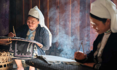H'mong women weaving textiles in a traditional setting, showcasing Vietnam's rich cultural heritage.