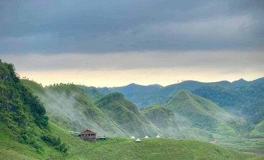 Hillside landscape with lush greenery and misty clouds over rural Hanoi, showcasing Vietnam's natura.