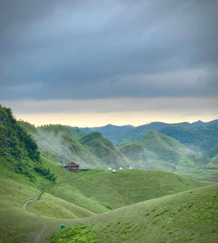 Hillside landscape with lush greenery and misty clouds over rural Hanoi, showcasing Vietnam's natura.