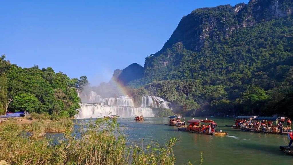 Halong Bay boat tour with stunning waterfalls and lush scenery.