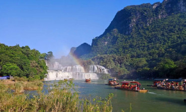 Halong Bay boat tour with stunning waterfalls and lush scenery.