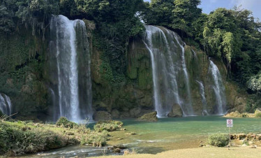 Waterfall view with lush greenery and tranquil water, perfect for relaxing in Northern Vietnam.