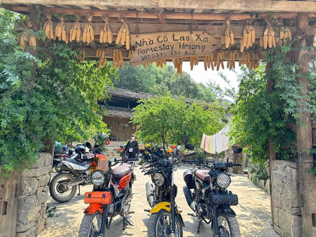 Homestay entrance with motorcycles and lush greenery, inviting travelers to experience local hospita.