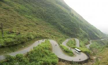 Ha Giang mountain pass winding through lush green hills.