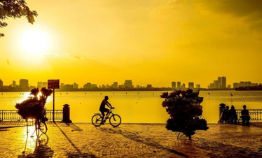 Hanoi cityscape at sunset with cyclists enjoying scenic views along the lake.