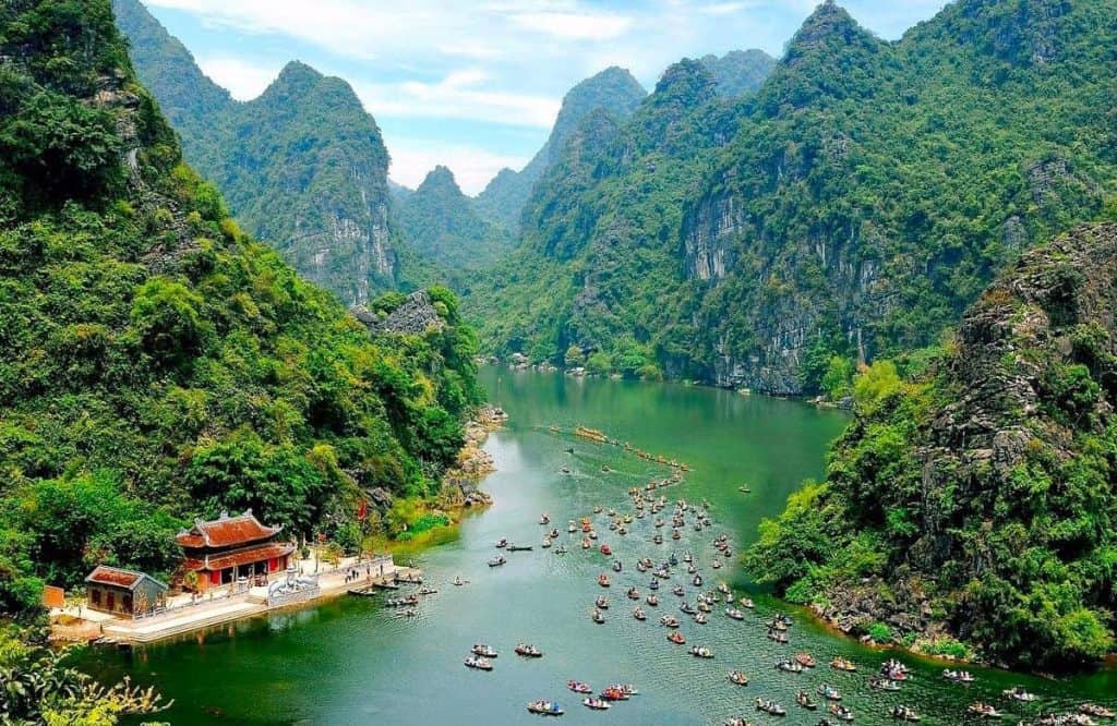 Halong Bay scenic cruise with lush green islands and emerald waters.