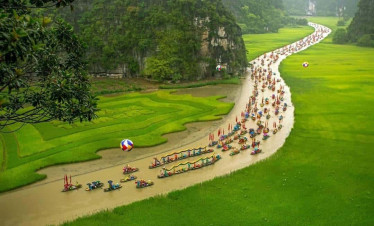 Halong Bay river cruise with colorful boats and lush green scenery.
