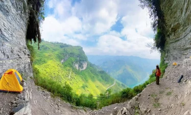 Mountains view from cave entrance with hikers exploring the scenic landscape.