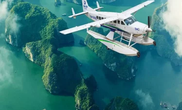 Seaplane flying over lush green islands and emerald waters in Vietnam.