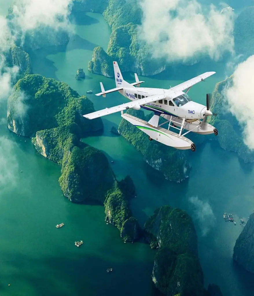 Seaplane flying over lush green islands and emerald waters in Vietnam.