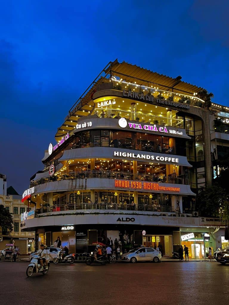 Highlands Coffee on a bustling street corner, vibrant evening atmosphere.