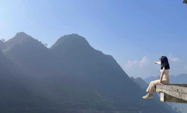 Ha Long Bay scenic viewpoint with woman enjoying the view on a ledge.