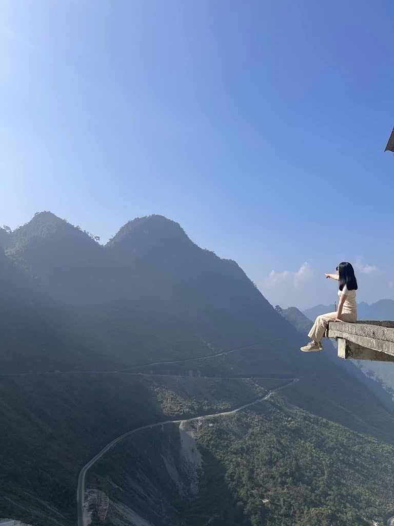 Ha Long Bay scenic viewpoint with woman enjoying the view on a ledge.