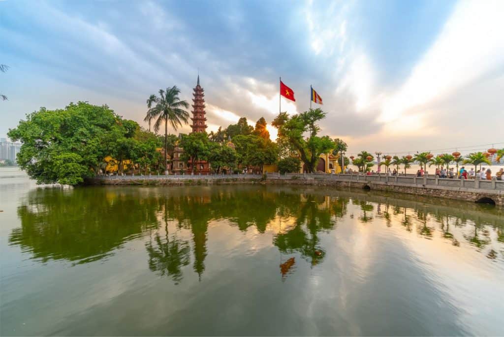 Hoan Kiem Lake scenic view with pagoda and flags, perfect for a peaceful Vietnam experience.