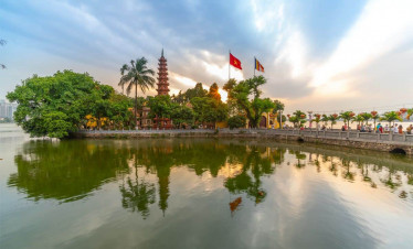 Hoan Kiem Lake scenic view with pagoda and flags, perfect for a peaceful Vietnam experience.