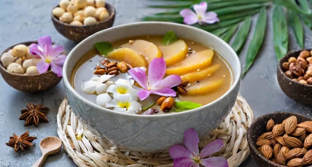 Vietnamese dessert with mango, coconut milk, and edible flowers.