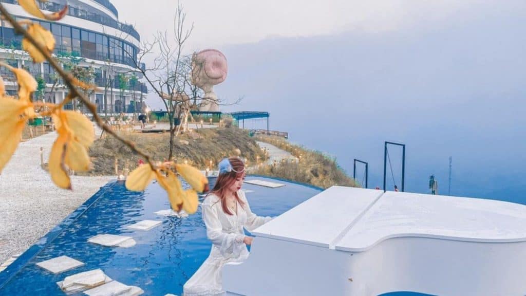 Sapa mountain view with fog and lush landscape, woman enjoying the scenery by a white grand piano.