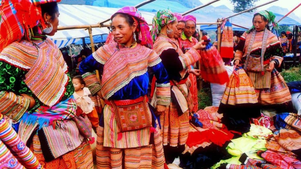 Vibrant traditional H'mong women showcasing colorful textiles at Sapa market, an authentic cultural.