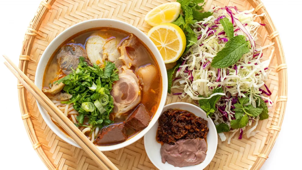 Vietnamese food bowl with herbs and lemon slices.