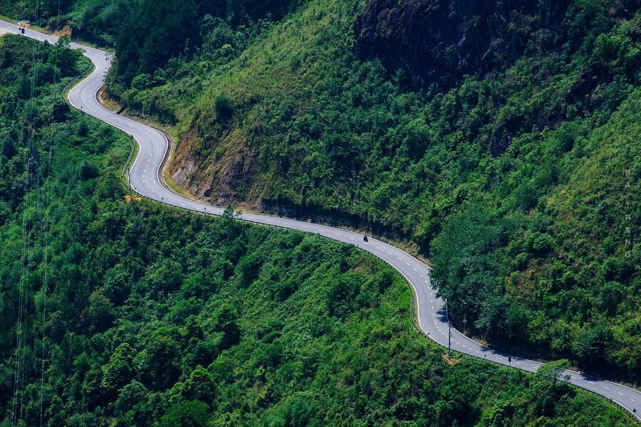 Sapa mountain road winding through lush green forests, offering breathtaking views and a peaceful es.
