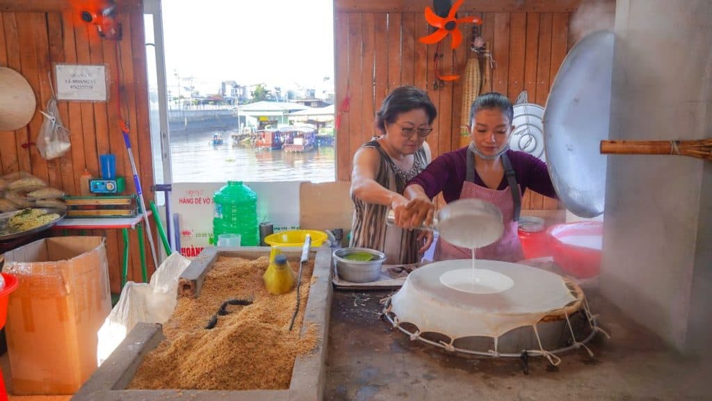 Mekong Delta women preparing traditional rice paper in a cozy local kitchen.