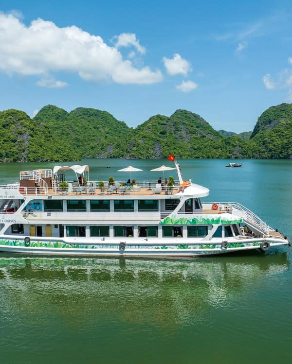 Serenity Cruise floating on tranquil Lan Ha Bay surrounded by lush green islands, offering a luxurio.