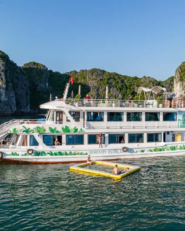 Serenity Cruise floating on tranquil Lan Ha Bay with stunning limestone karsts.