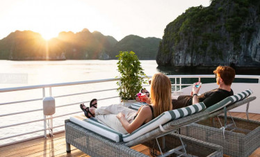 Serenity Cruise guests relaxing on deck with stunning sunset views over Lan Ha Bay.
