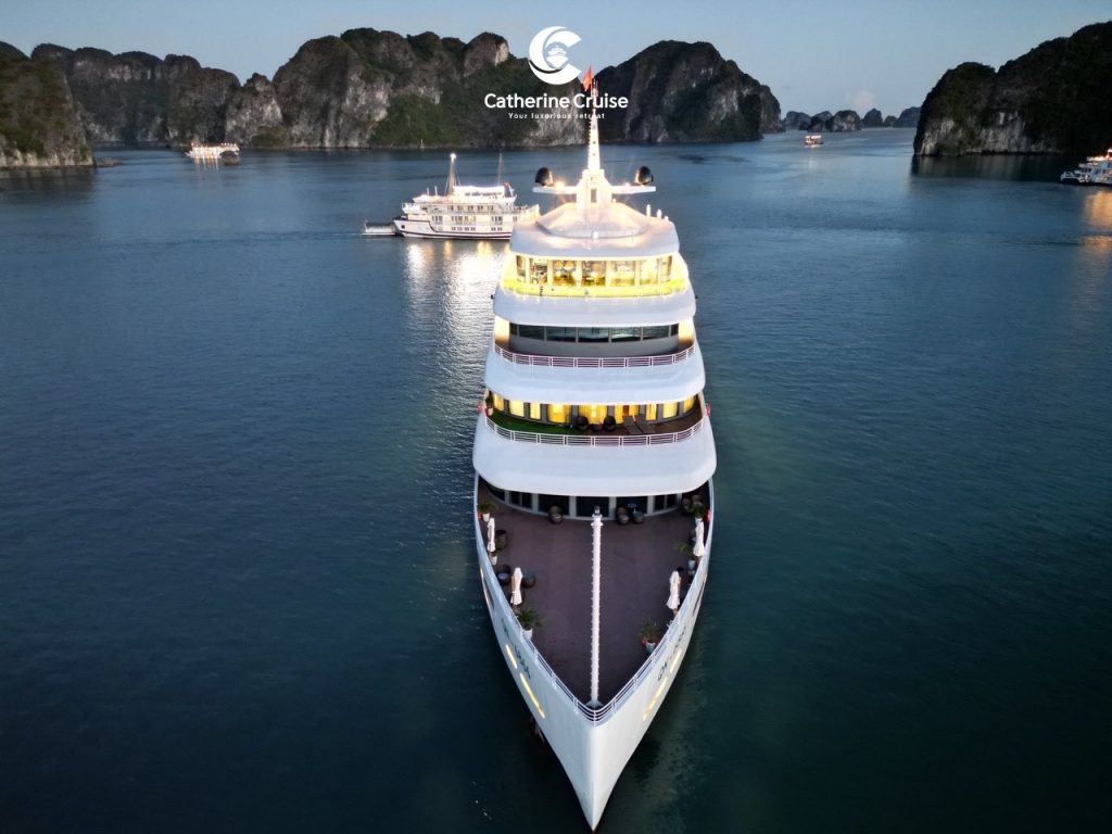 Luxurious cruise ship sailing in emerald waters among limestone karsts in Ha Long Bay.