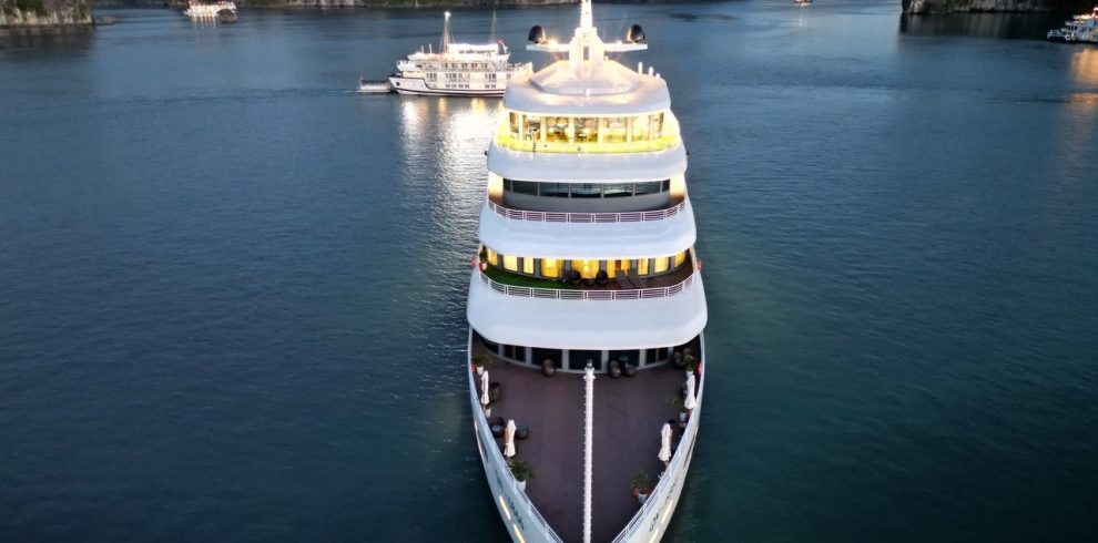 Luxurious cruise ship sailing in emerald waters among limestone karsts in Ha Long Bay.