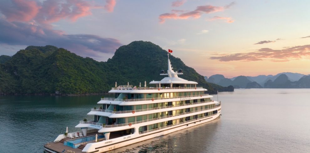 Luxury cruise ship sailing in Ha Long Bay at sunset, scenic limestone islands, Vietnam tourism.