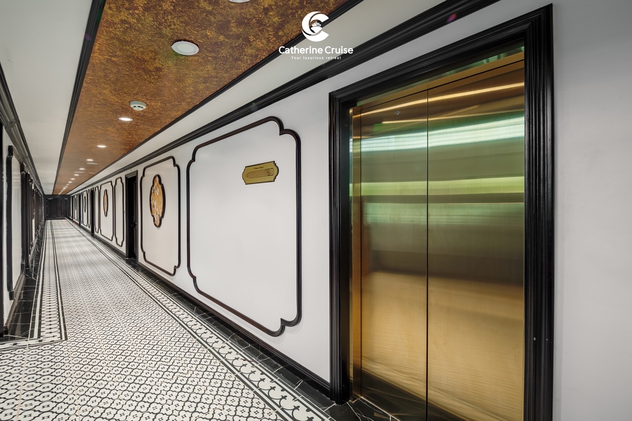 Modern hotel corridor with elegant black and white decor and gold elevator doors.