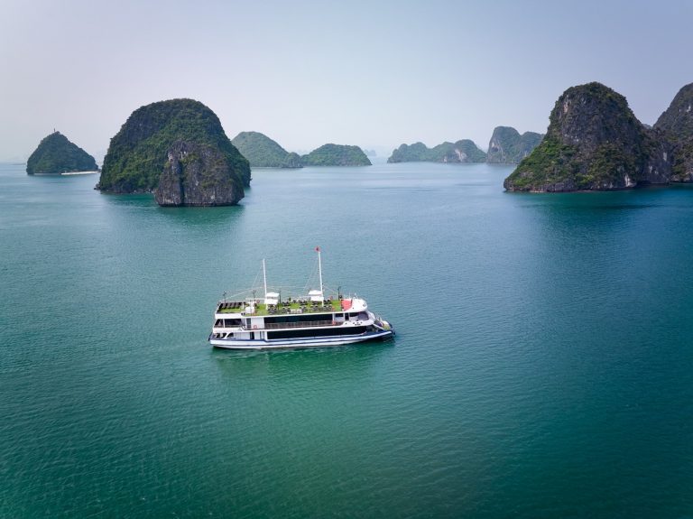 Beautiful Halong Bay landscape with a cruise boat sailing among limestone islands.