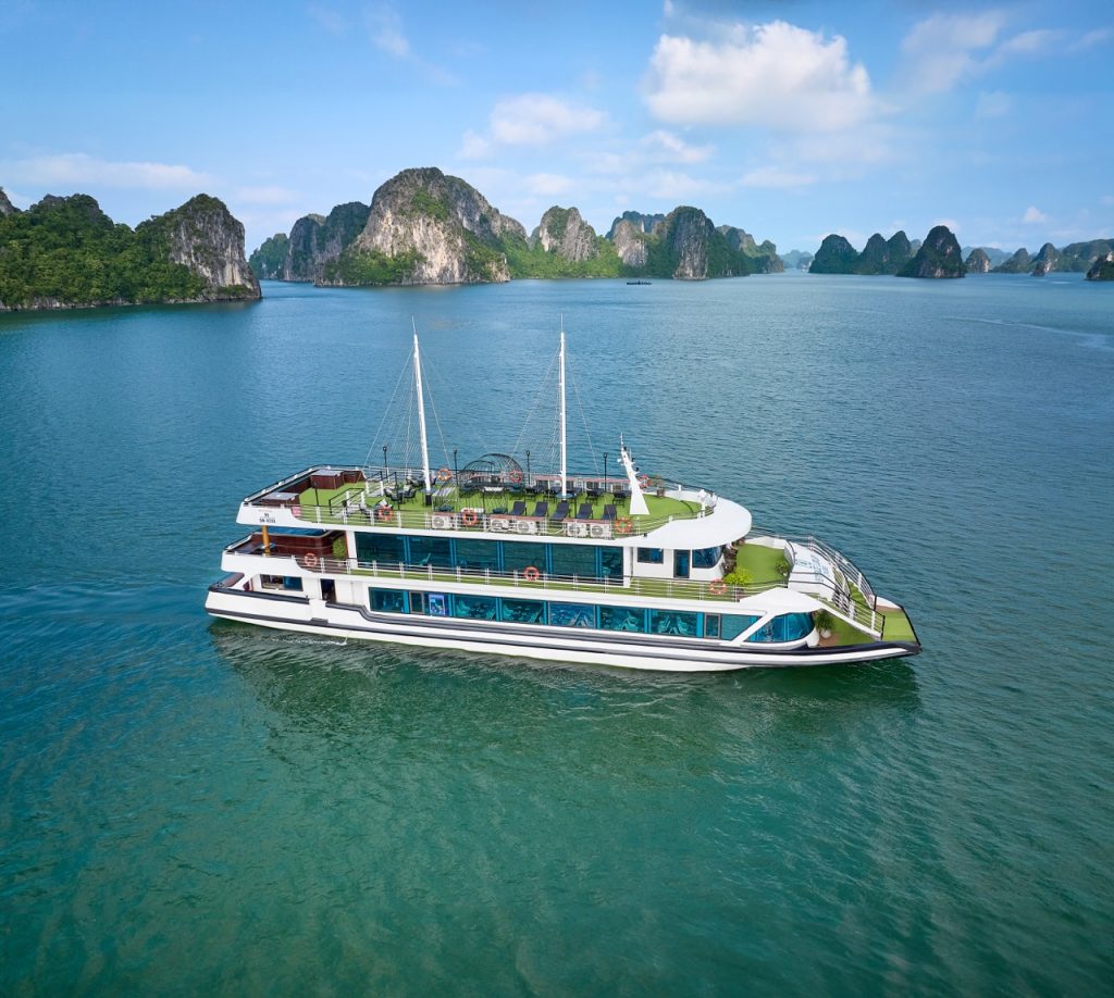 Luxury cruise boat sailing on Halong Bay with limestone karsts and emerald waters.