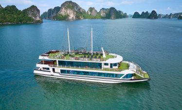Luxury cruise boat sailing on Halong Bay with limestone karsts and emerald waters.