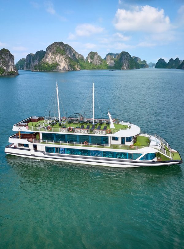 Luxury cruise boat sailing on Halong Bay with limestone karsts and emerald waters.