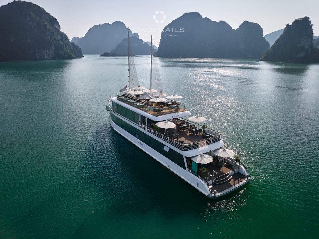 Halong Bay cruise boat sailing through emerald waters with limestone karsts, perfect for scenic expl.