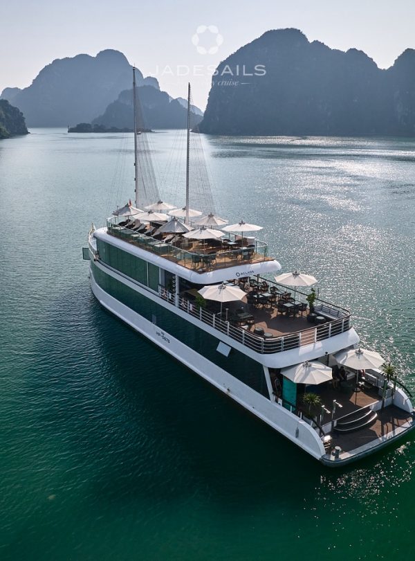 Halong Bay cruise boat sailing through emerald waters with limestone karsts, perfect for scenic expl.