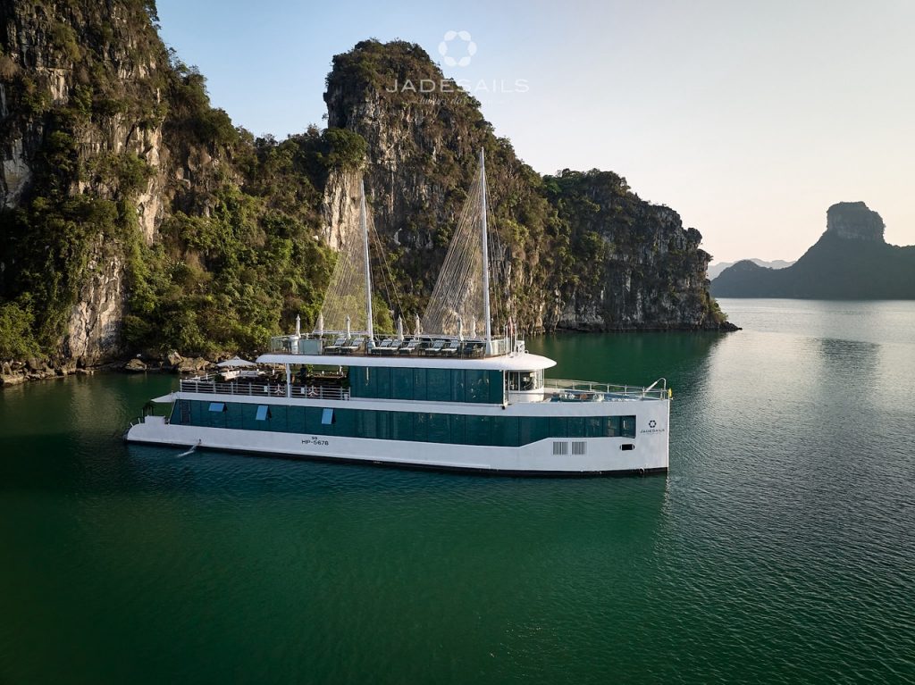 Elegant cruise boat sailing in Halong Bay with limestone karsts and emerald waters.