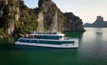 Elegant cruise boat sailing in Halong Bay with limestone karsts and emerald waters.