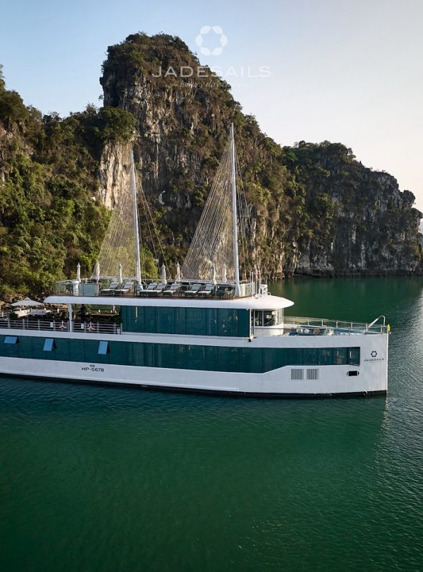 Elegant cruise boat sailing in Halong Bay with limestone karsts and emerald waters.