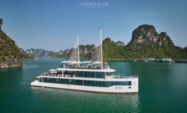 Elegant cruise boat sailing on Halong Bay with limestone karsts and clear waters.