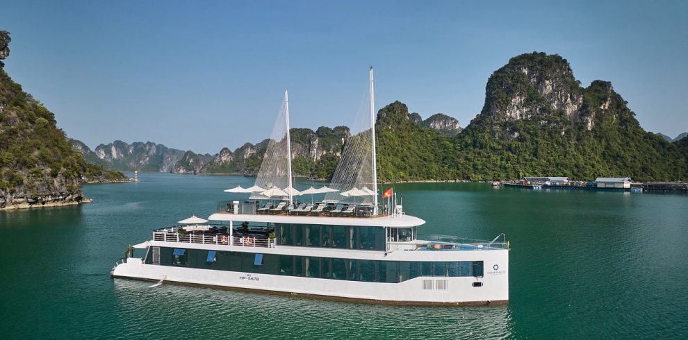 Elegant cruise boat sailing on Halong Bay with limestone karsts and clear waters.