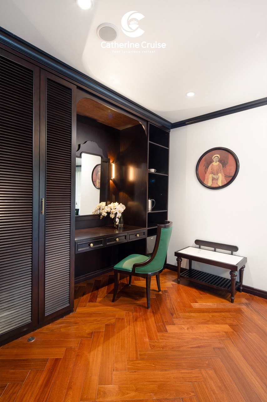 Elegant hotel room vanity with mirror, green chair, and wooden flooring, perfect for relaxing stays.