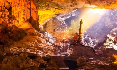 Beautiful cave interior with stalactites and stalagmites illuminated by warm light, perfect for adve.