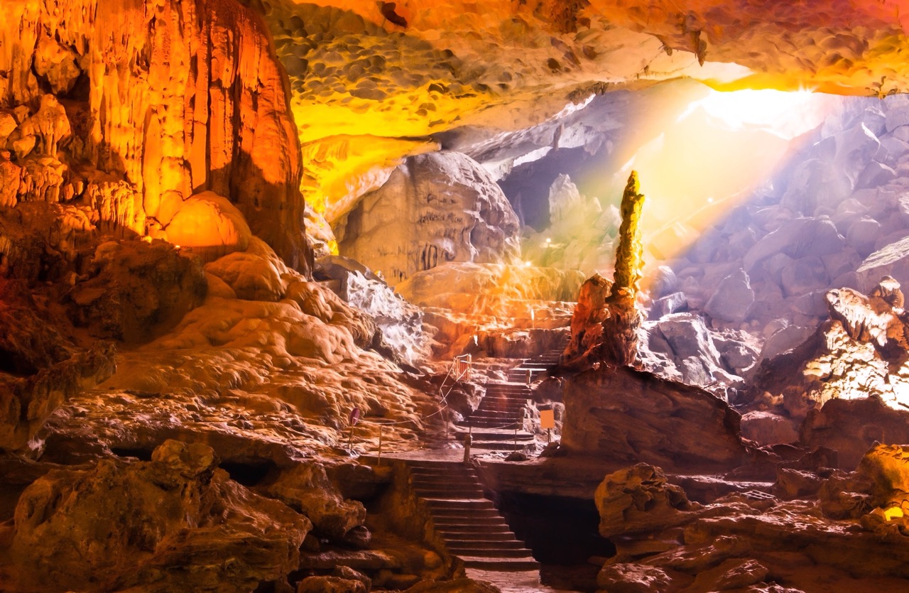 Beautiful cave interior with stalactites and stalagmites illuminated by warm light, perfect for adve.