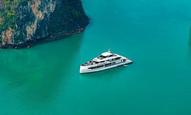 Luxury yacht cruising in Halong Bay with emerald waters and towering limestone karsts.