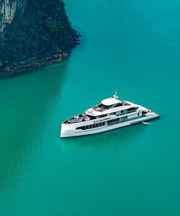 Luxury yacht cruising in Halong Bay with emerald waters and towering limestone karsts.
