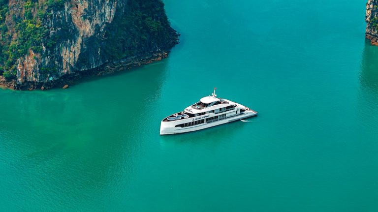 Luxury yacht cruising in Halong Bay with emerald waters and towering limestone karsts.